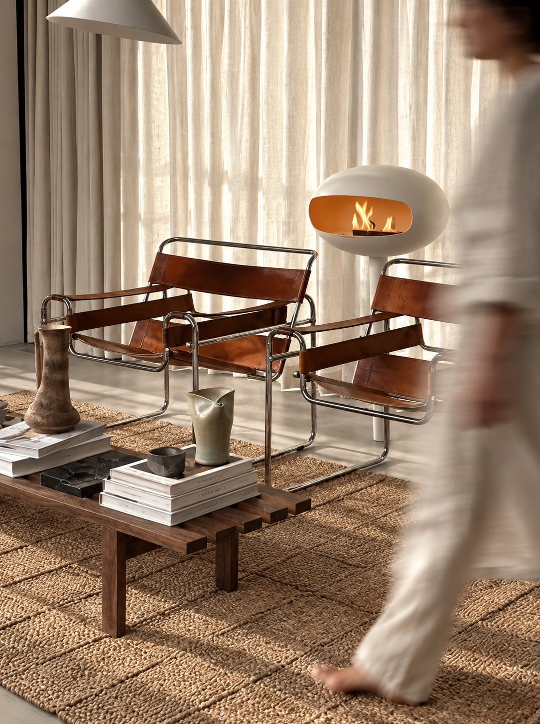Sophia white bioethanol fireplace lit in a living room with leather armchair, ARDĒO